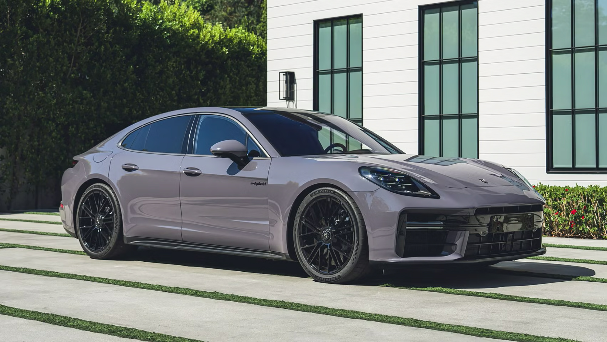 picture took from the the side of a grey purple porsche panamera turbo while being in front of a side of a nice residents home